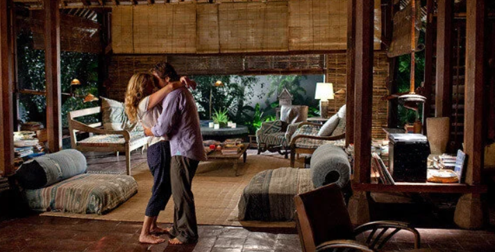 Liz and Felipe embrace in a wooden Balinese house — the final scene of the Bali chapter