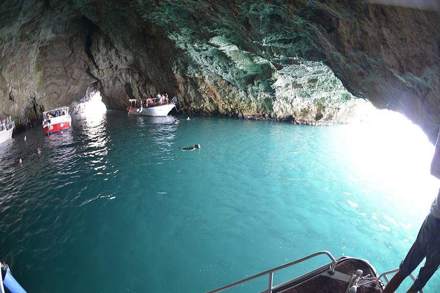 The Blue Cave Plava špilja on Luštica peninsula Montenegro with neon-blue glowing water and a small boat at the entrance