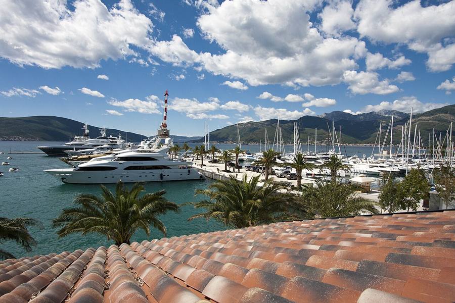 Yachts moored at the Porto Montenegro marina in Tivat with green hills and the Bay of Kotor in the background